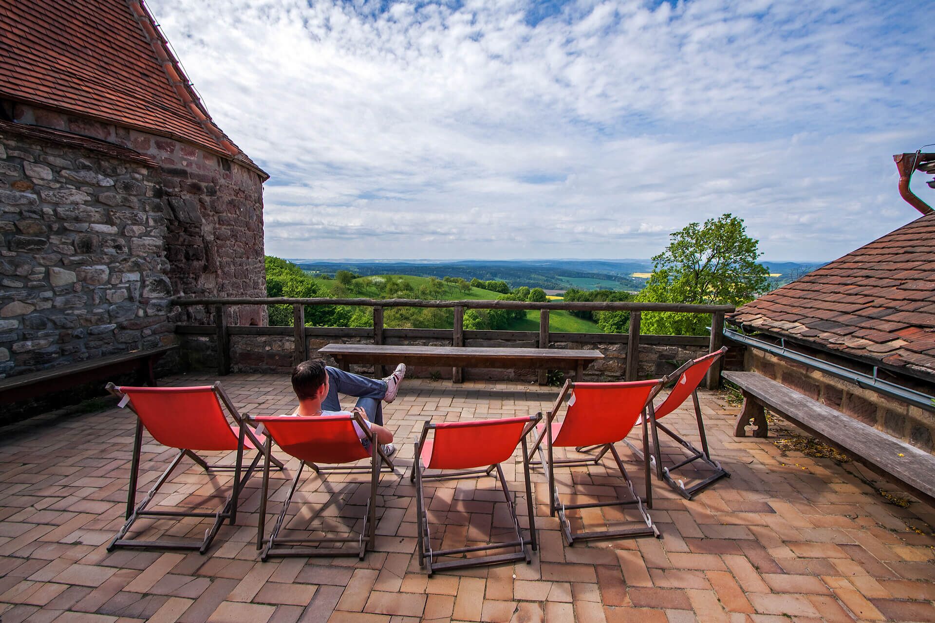 Besucher veweilt in Liegestuhl auf Terrasse mit Blick auf´s Saaletal