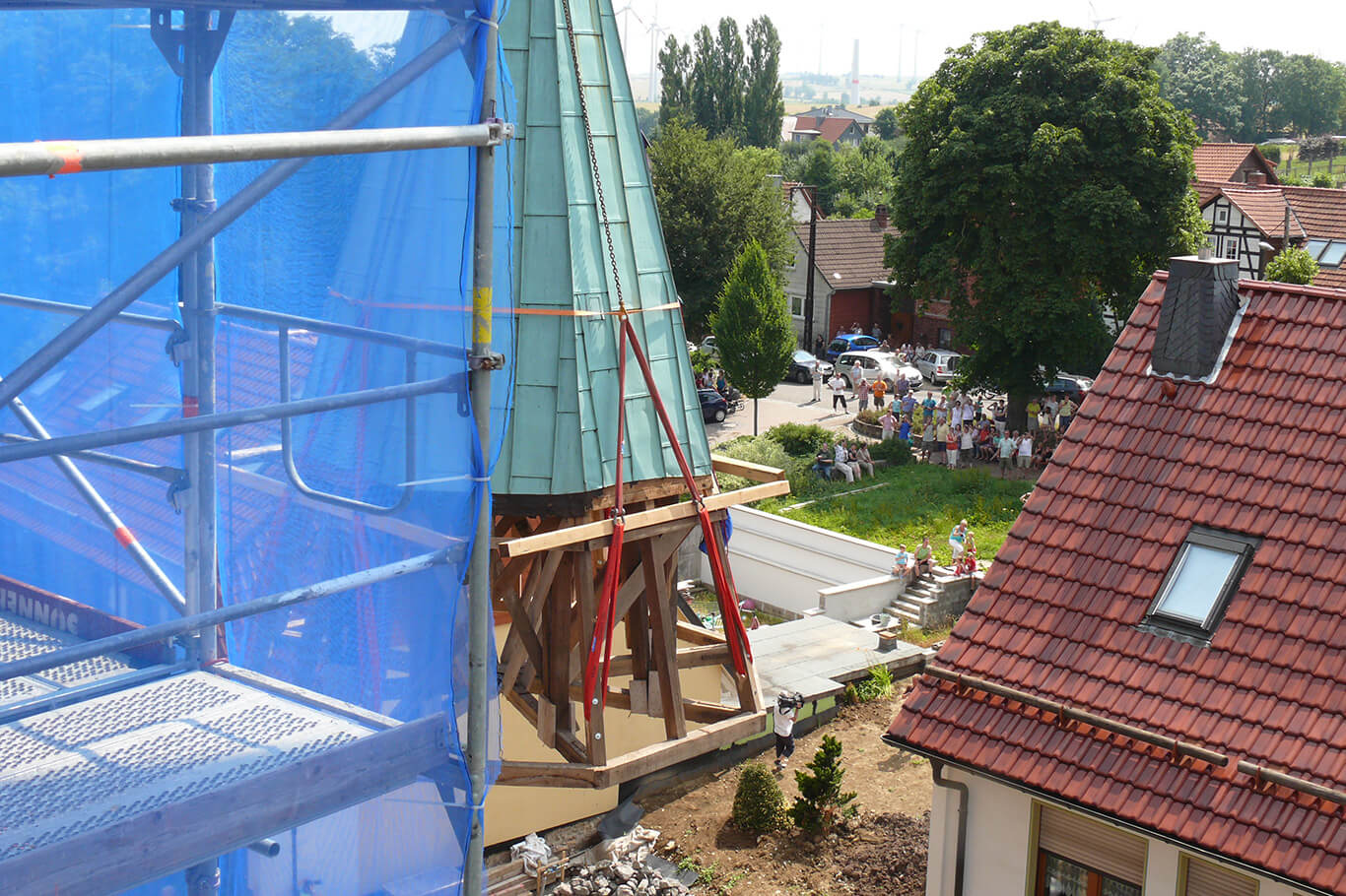 Detailansicht des durch einen Kran angehobenen neuen Turmhelms für den Kirchturm Küllstedt
